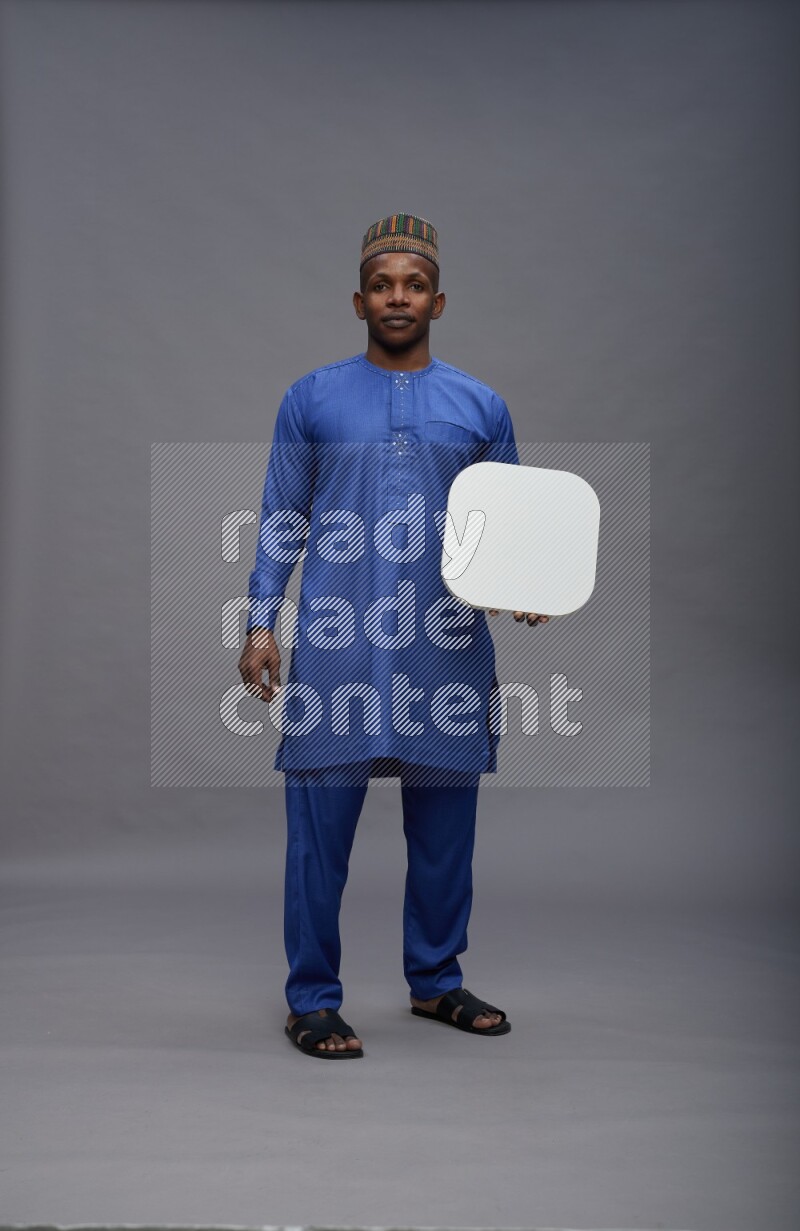 Man wearing Nigerian outfit standing holding social media sign on gray background