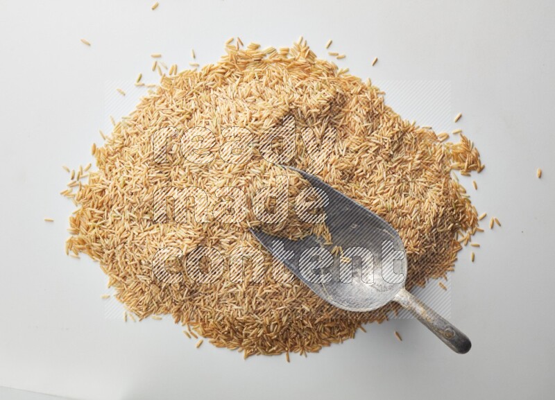 Top-view of a long grain brown rice, and shovel on white background