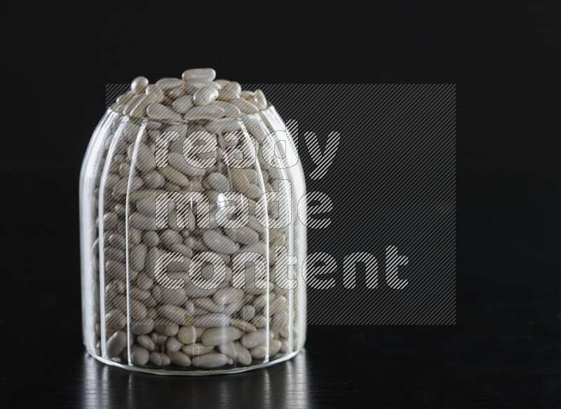 White beans in a glass jar on black background
