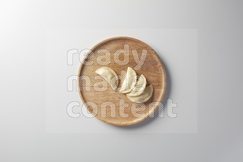 Four Sambosas on a wooden round plate on a white background