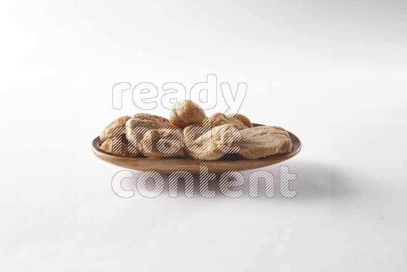 Dried figs in a wooden plate on white background