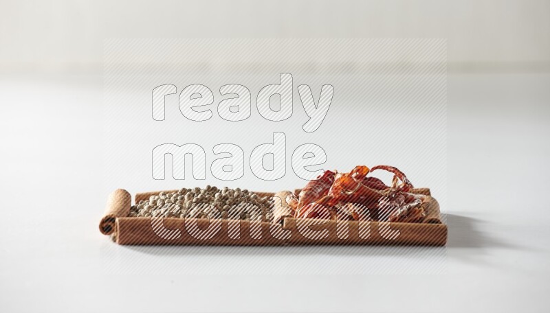 2 squares of cinnamon sticks full of red dried chilis and white pepper on white flooring