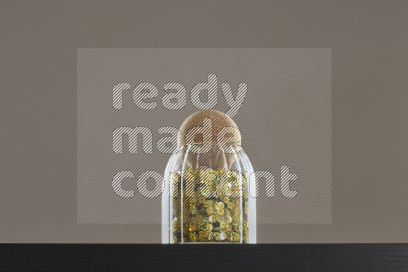 Sequins in a glass jar on black background