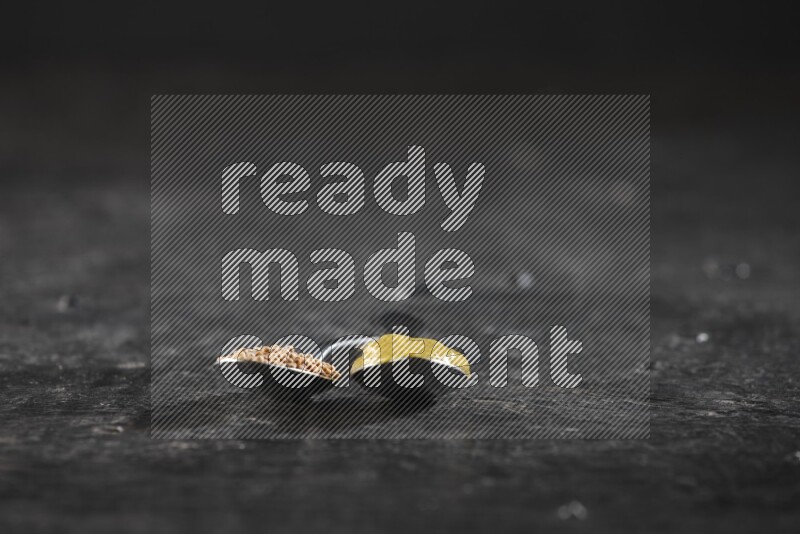 Two metal spoons, one filled with mustard seeds and the other with mustard paste on black background