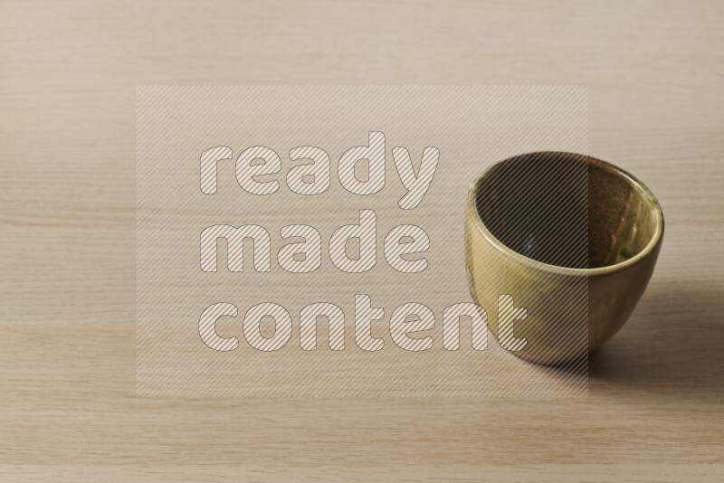 A multicolored pottery cup on light wooden background