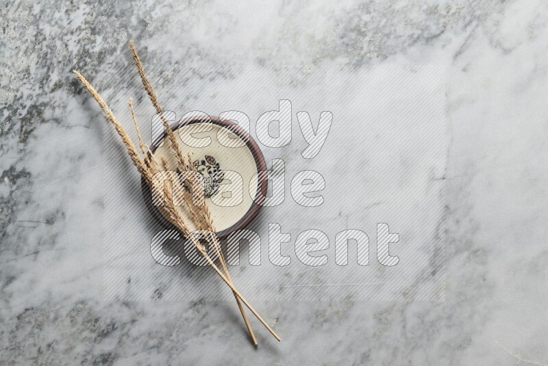 Wheat stalks on decorative pottery plate on grey marble background