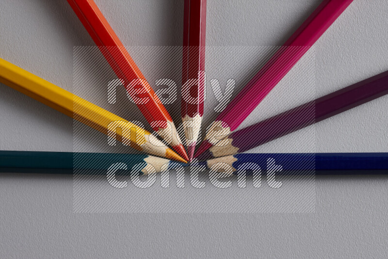 An arrangement of colored pencils in different colors on grey background