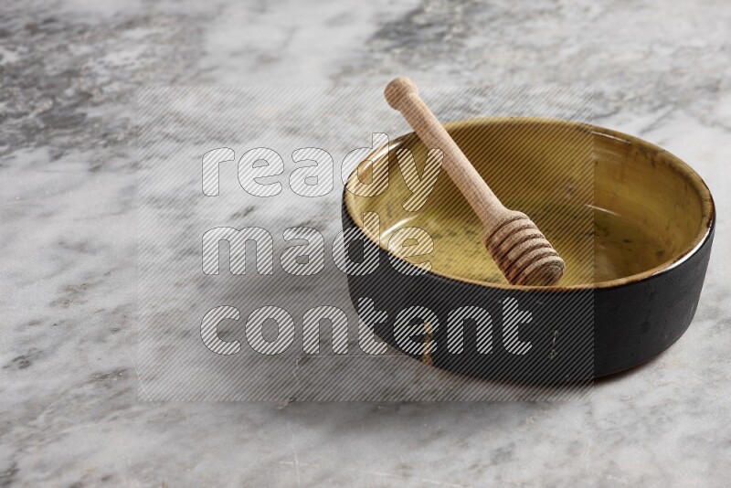 Multicolored Pottery Oven Plate with wooden honey handle in it, on grey marble flooring, 45 degree angel