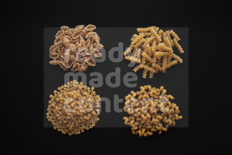 Different pasta types in bunches on black background