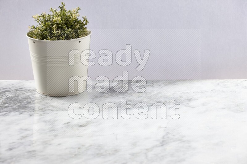 Artificial plant in white pot on grey marble background