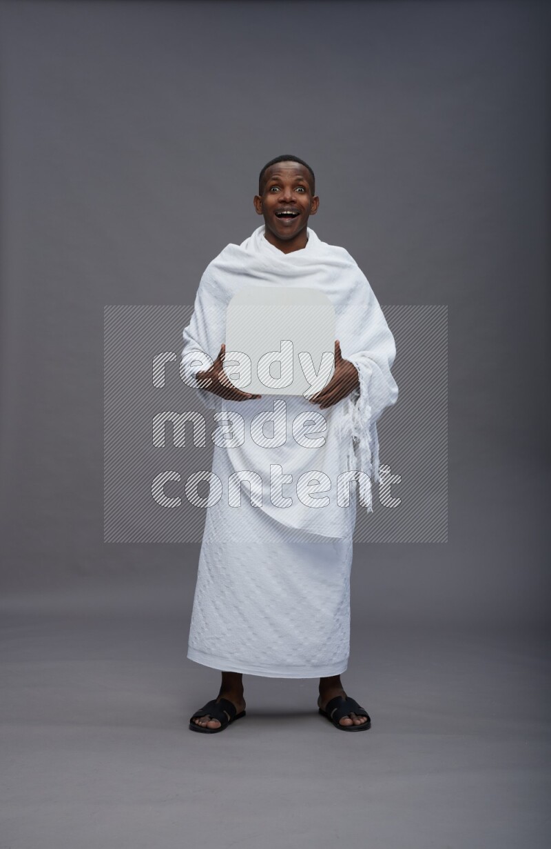 A man wearing Ehram Standing holding social media sign on gray background