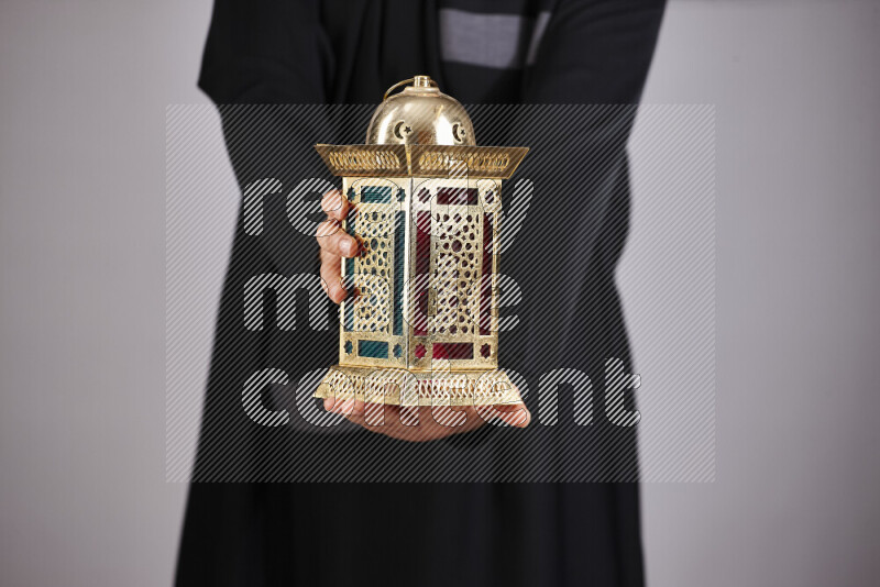 A woman in black abaya holding different ramadan lanterns in different positions