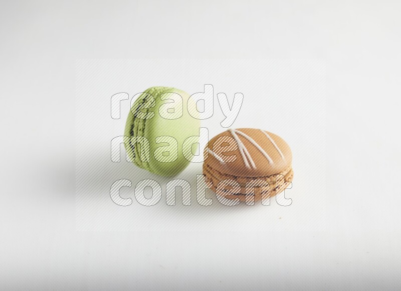 45º Shot of of two assorted Brown Irish Cream, and Green Pistachio macarons on white background