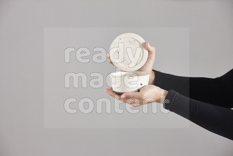 A woman in black abaya holding different pottery essentials in different positions