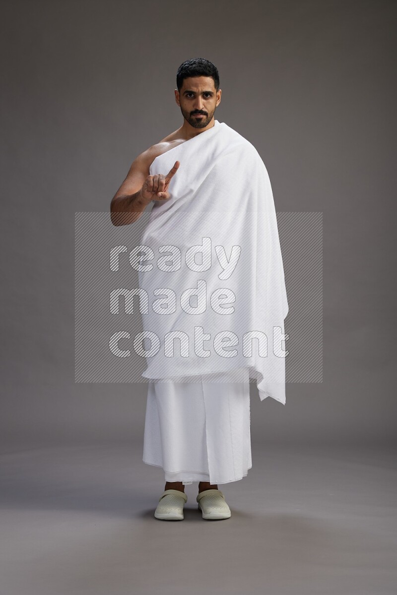 A man wearing Ehram Standing Interacting with the camera on gray background