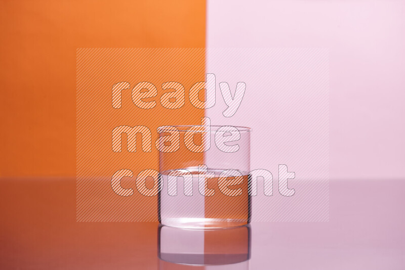 The image features a clear glassware filled with water, set against orange and rose background