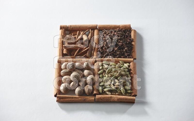 4 squares of cinnamon sticks full of cardamom, cinnamon, cloves and nutmeg on white flooring