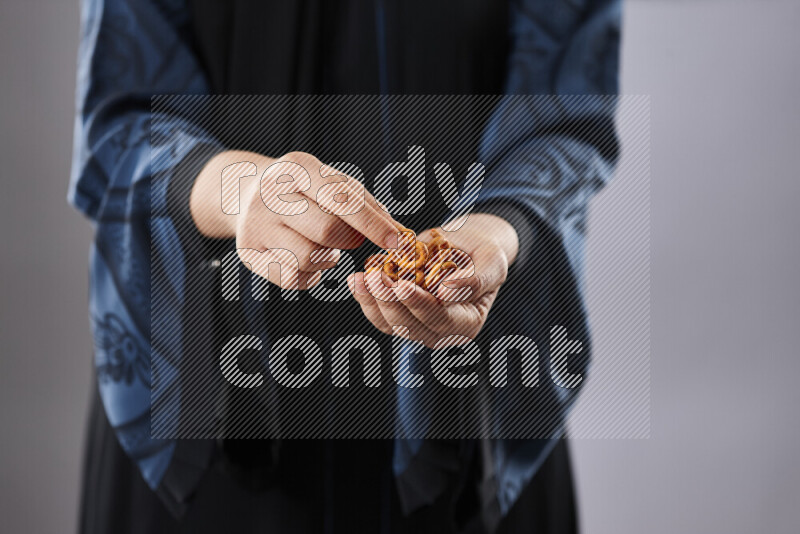 Woman in abaya holding different kinds of snacks in different positions
