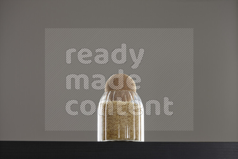 Basmati golden rice in a glass jar on black background