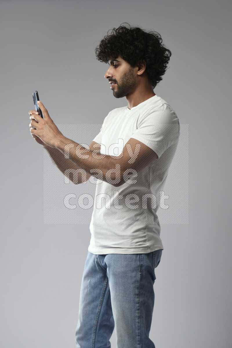 A man wearing casual standing and shooting with his phone on white background