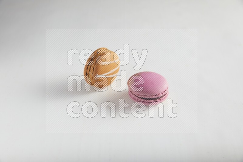 45º Shot of of two assorted Brown Irish Cream, and Purple Strawberry macarons on white background