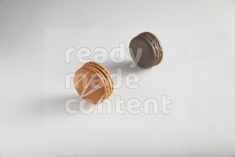 45º Shot of of two assorted Brown Irish Cream, and Brown Dark Chocolate macarons on white background