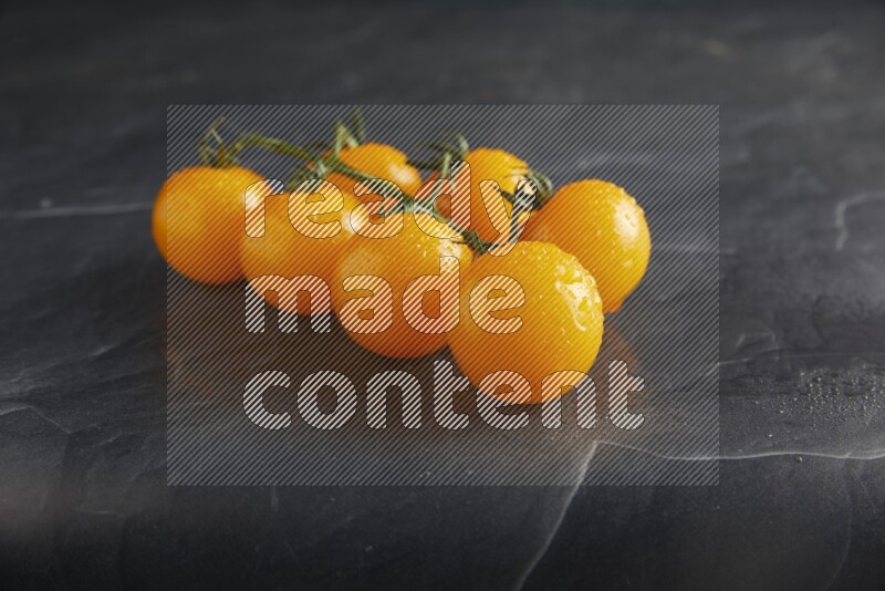 Yellow cherry tomato vein on a textured black slate background 45 degree