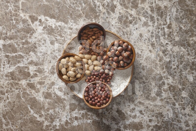 Nuts in pottery plates and wooden bowls in a light setup