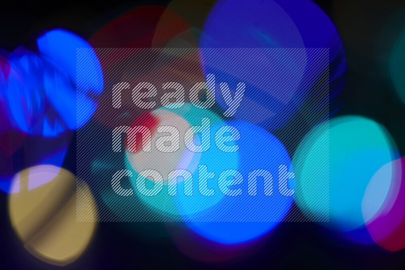 Light bulbs glowing against backdrop of multicolord bokeh