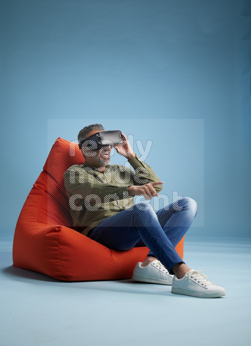 A man sitting on an orange beanbag and gaming with VR
