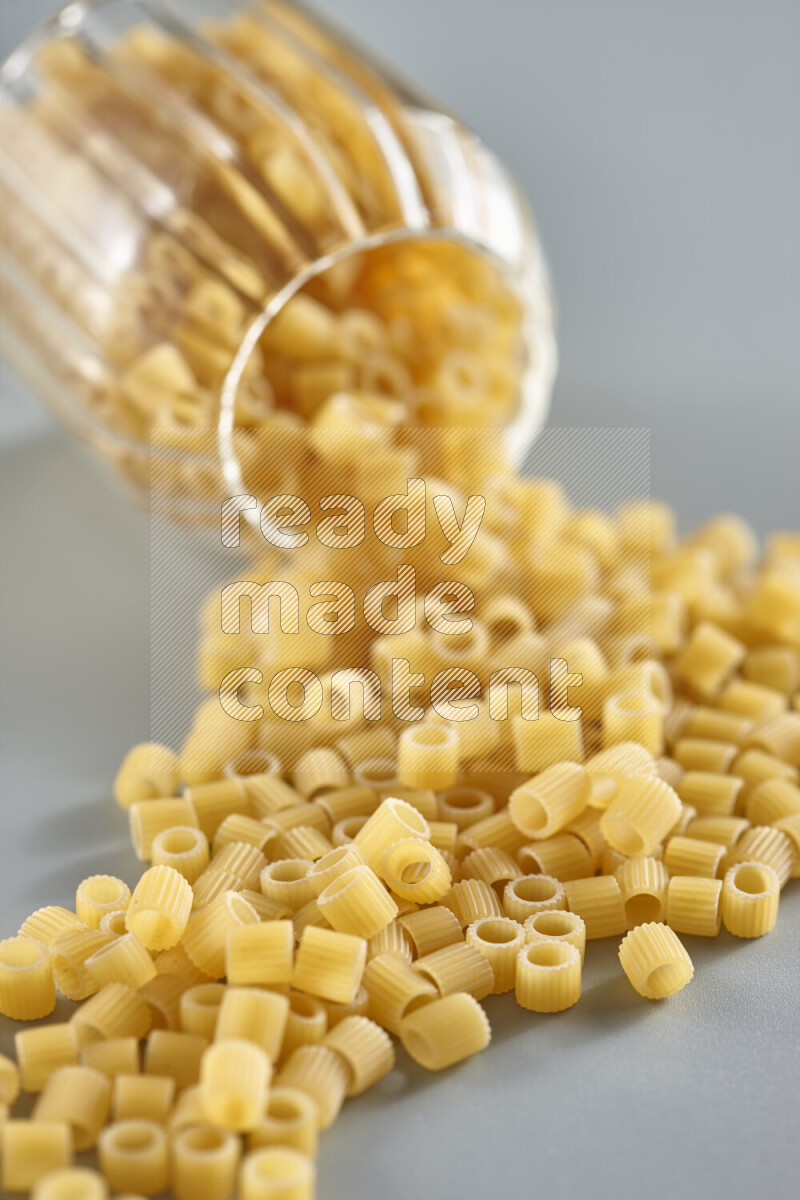 Flipped jar full of raw pasta on light blue background