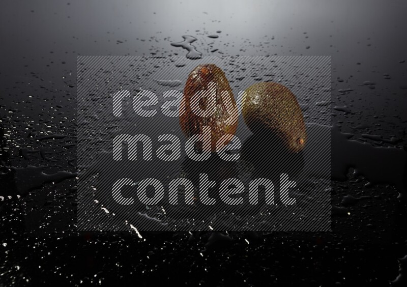 A whole avocado on black background with water drops.