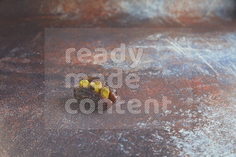 one pistachio stuffed madjoul date on a rustic reddish background