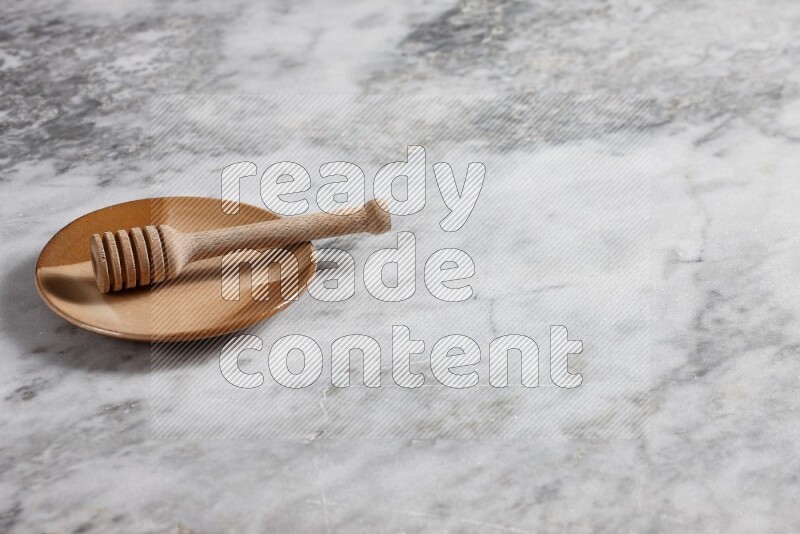 Multicolored pottery plate with wooden honey dipper in it on grey marble background