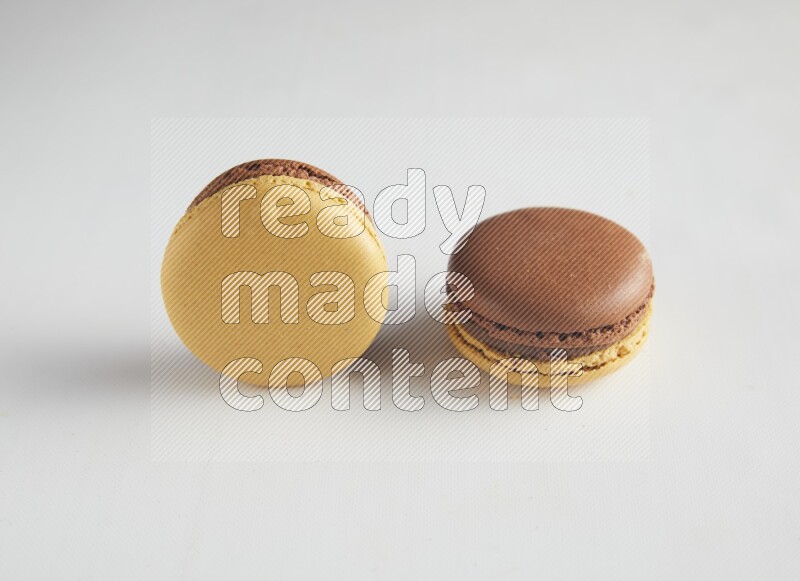 45º Shot of two Yellow and Brown Chai Latte macarons on white background