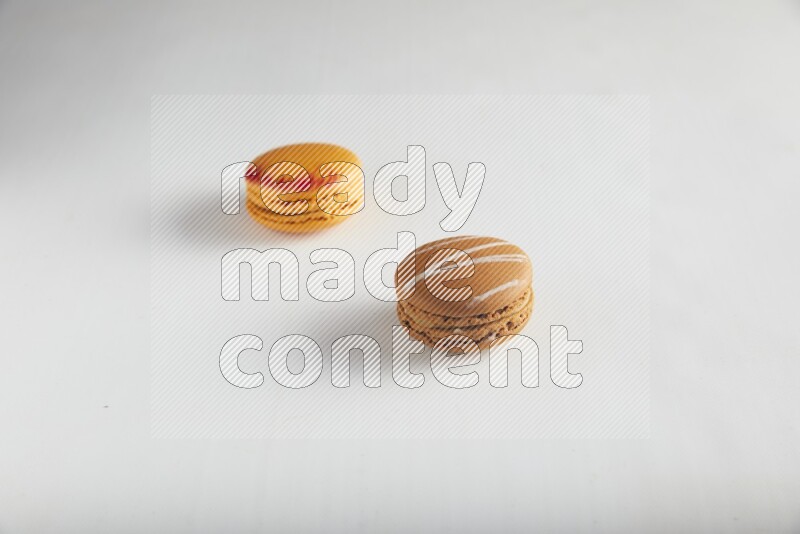 45º Shot of of two assorted Brown Irish Cream, and Orange Exotic macarons on white background