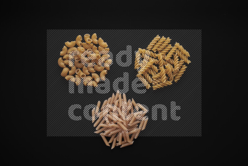 Different pasta types in bunches on black background