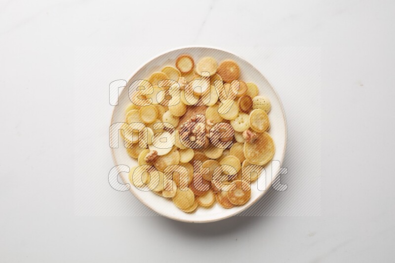 Top-view shot of walnut cereal pancakes in a round bowl on white background