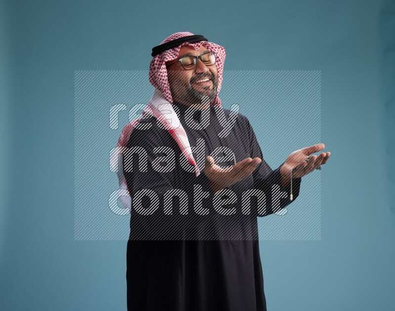 Saudi Man with shimag Standing Interacting with the camera on blue background