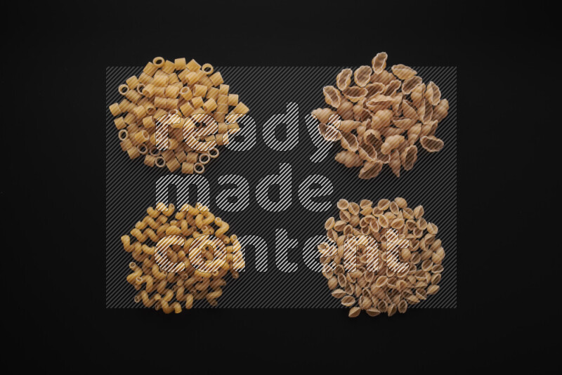 Different pasta types in bunches on black background