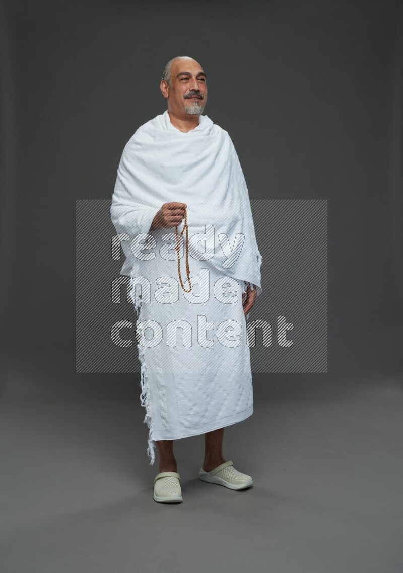A man wearing Ehram Standing holding rosary on gray background