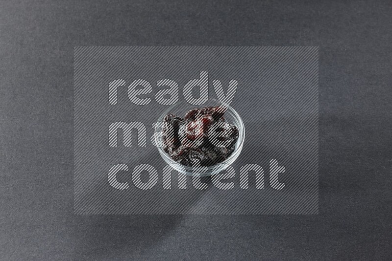 وعاء زجاجي ممتلئ بالبرقوق المجفف على خلفية سوداء