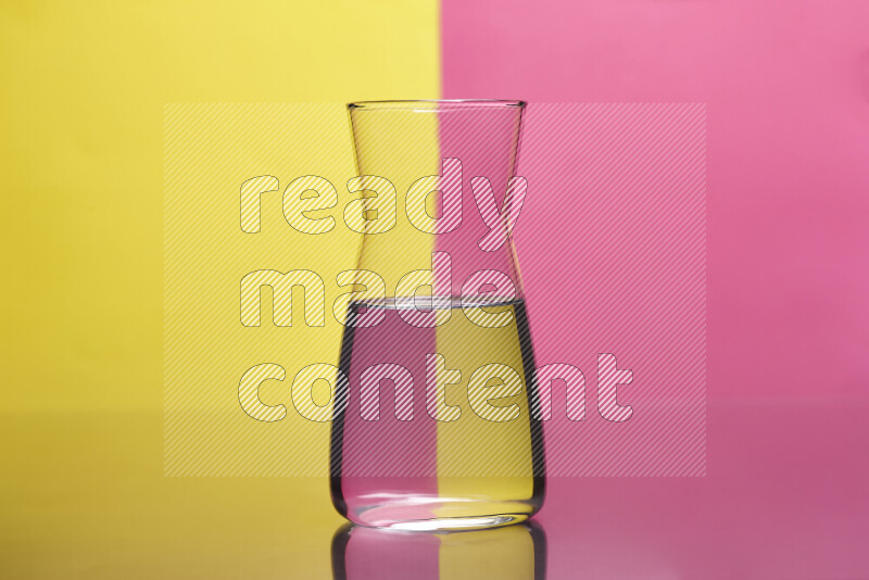 The image features a clear glassware filled with water, set against yellow and pink background