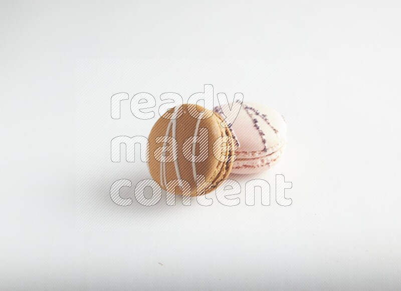 45º Shot of of two assorted Brown Irish Cream, and pink orange blossom macarons on white background
