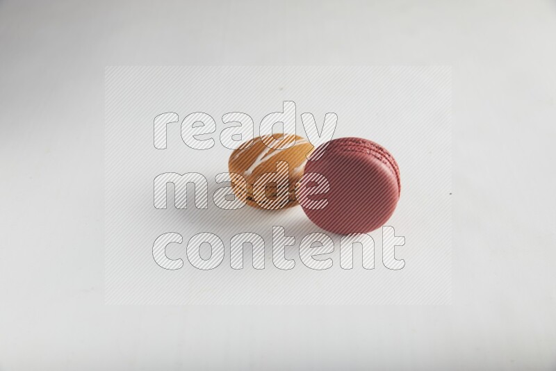 45º Shot of of two assorted Brown Irish Cream, and Red Velvet macarons on white background