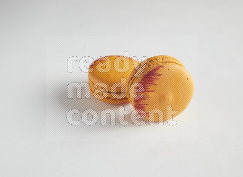 45º Shot of two orange Exotic macarons on white background
