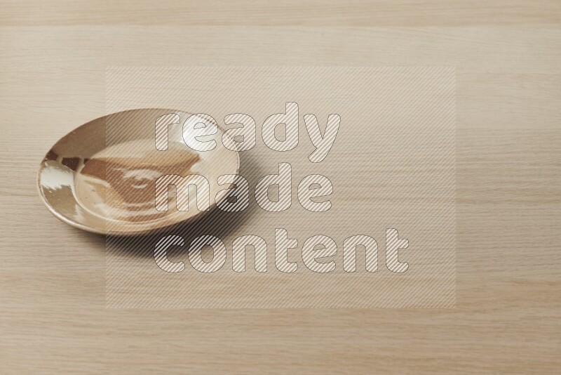 A multicolored pottery plate on light wooden background