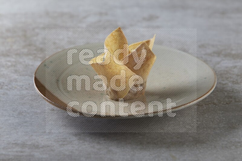 wonton cups with soy sauce ramkin on multi colored pottery on grey textured counter top