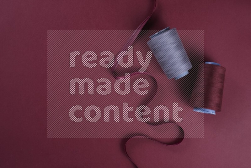 مجموعة من أدوات الخياطة والتفصيل رمادية اللون على خلفية حمراء