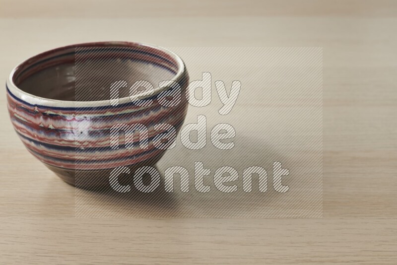 A multicolored pottery bowl on light wooden background